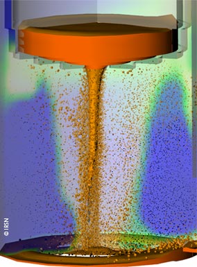 Visualisation d’une simulation 3D par le logiciel MC3D de la dispersion du corium (en rouge) dans l’eau (dégradé bleu/blanc)contenu dans le puits de cuve en cas de percement central du fond de la cuve. Les points oranges et noirs représentent les gouttes de corium(oranges si elles sont liquides, noires si elles sont solides). La géométrie du puits de cuve est simplifiée.